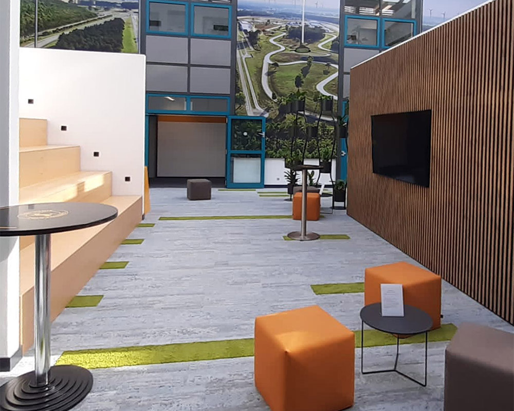 Videoecke mit TV-Wand, Sitzwürfeln und Lounge-Tischen in modernem Bürokontext
